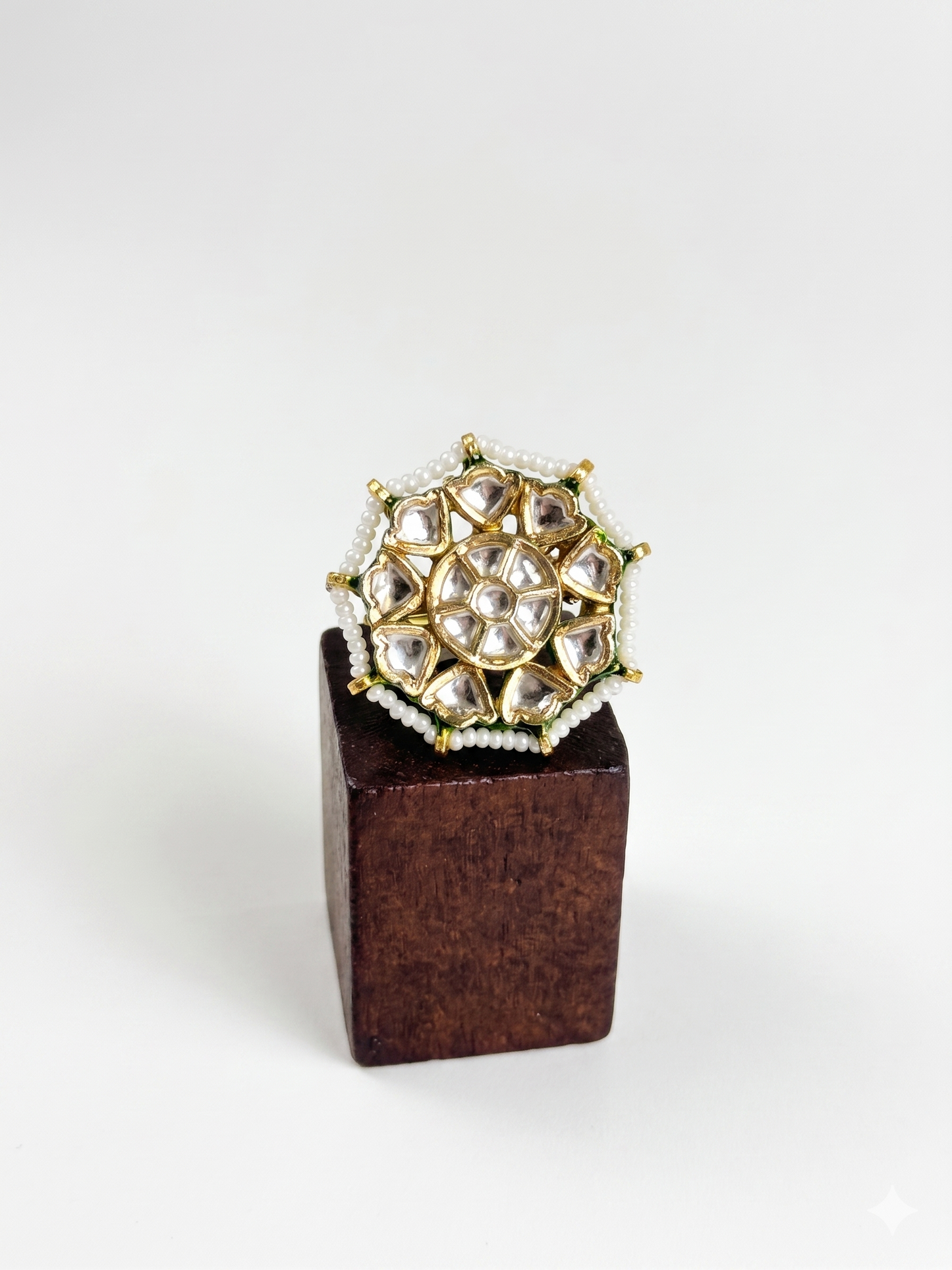 Gold and pearl ring on a wooden block against a white background