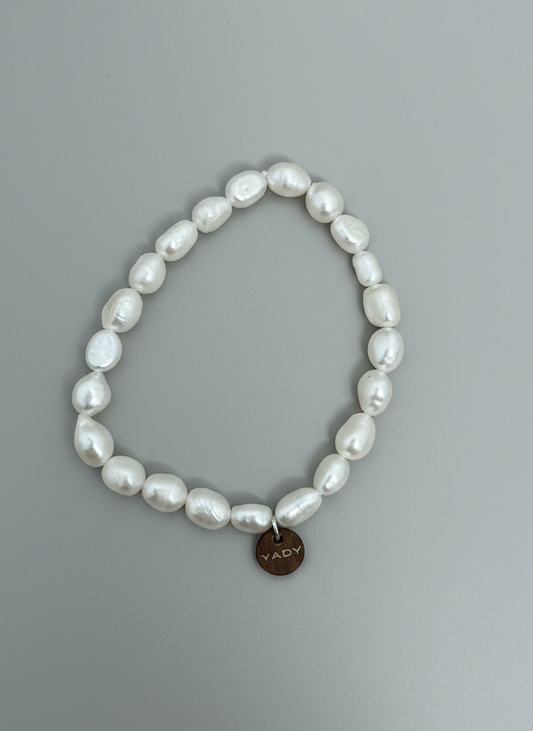 Pearl bracelet with a heart-shaped tag on a gray background