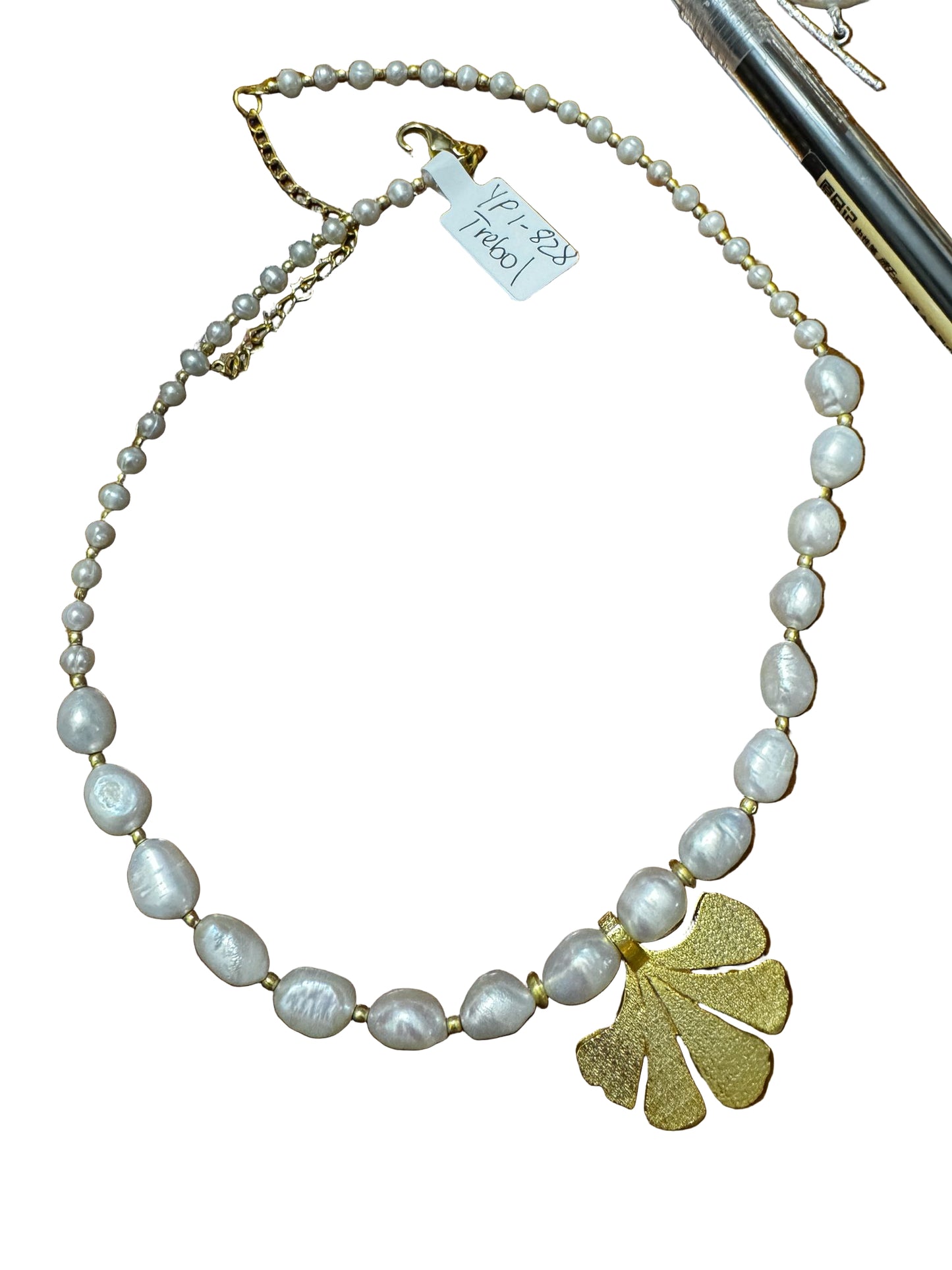 Pearl necklace with a gold leaf pendant on a wooden surface