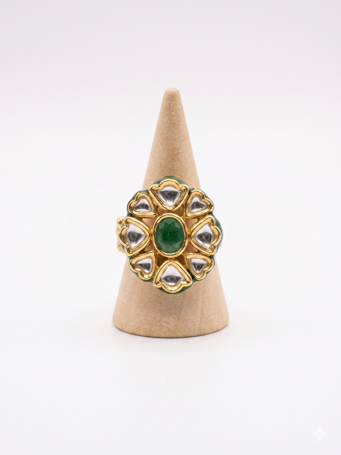Gold ring with green gemstone on a beige cone stand against a white background