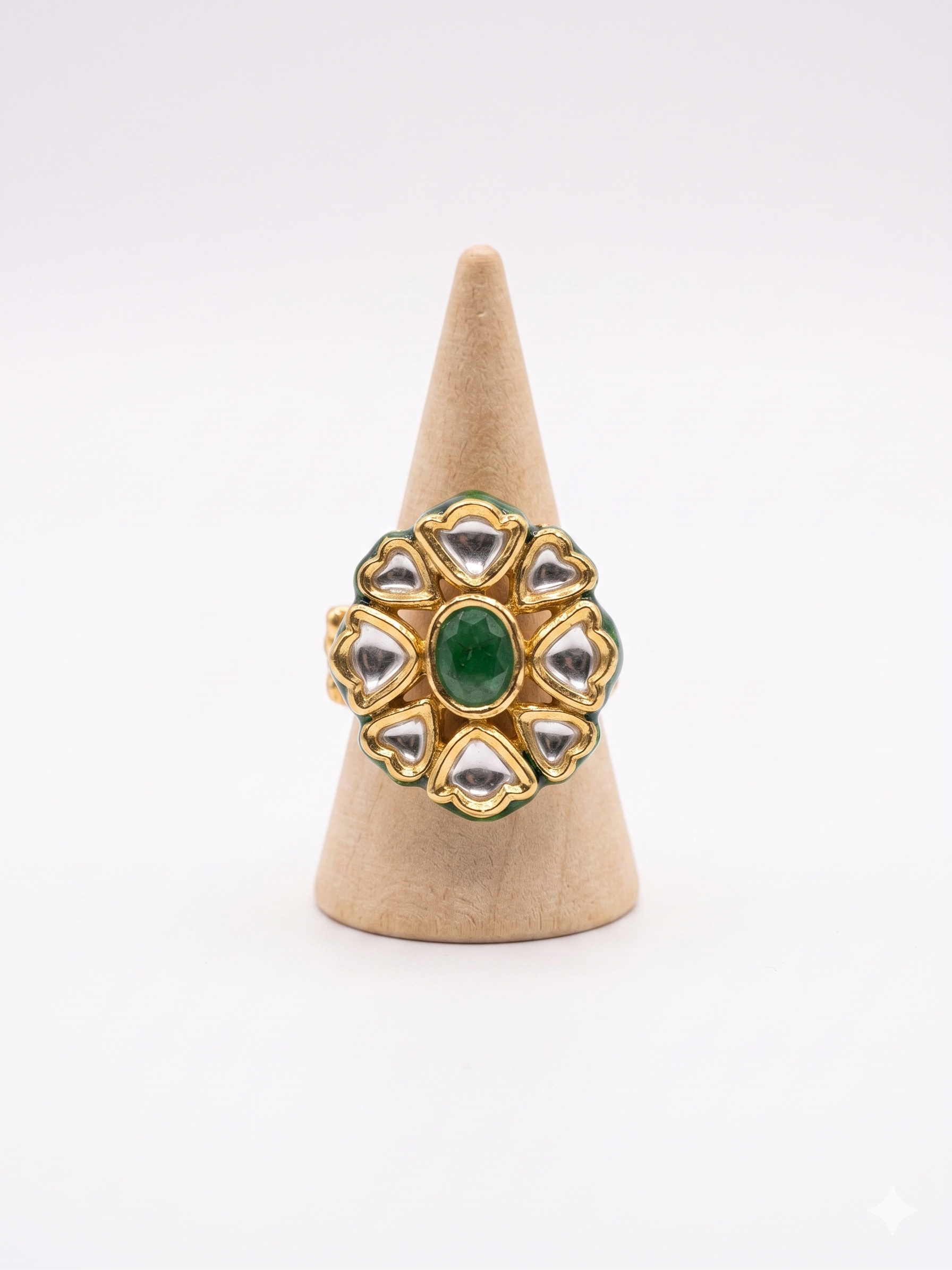 Gold ring with green gemstone on a beige cone stand against a white background