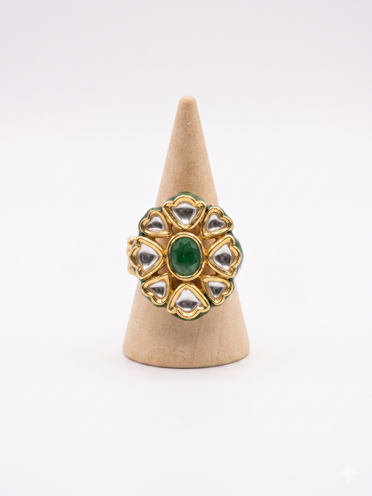 Gold ring with green gemstone on a beige cone stand against a white background