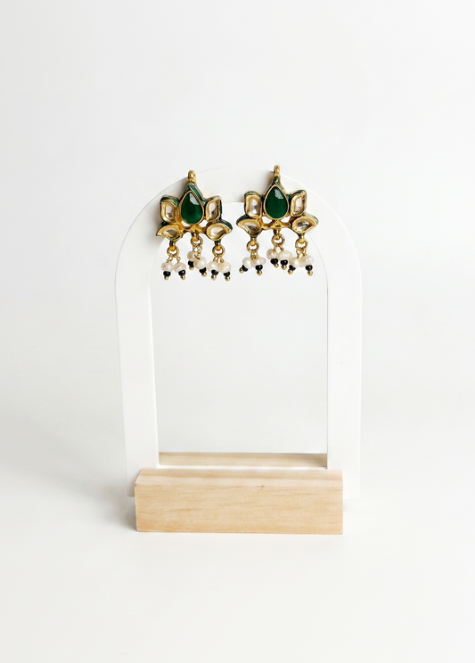 Pair of gold and green earrings on a white stand with a white background