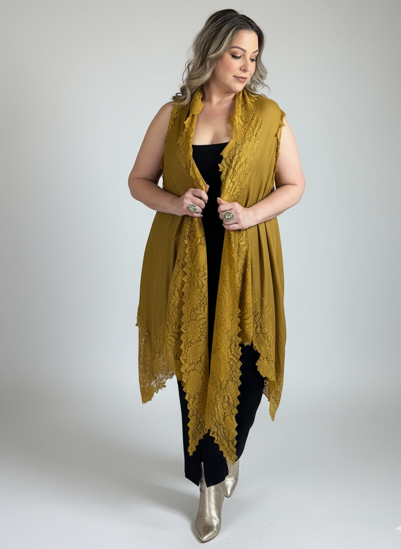 Woman wearing a mustard yellow lace vest over a black outfit on a plain background