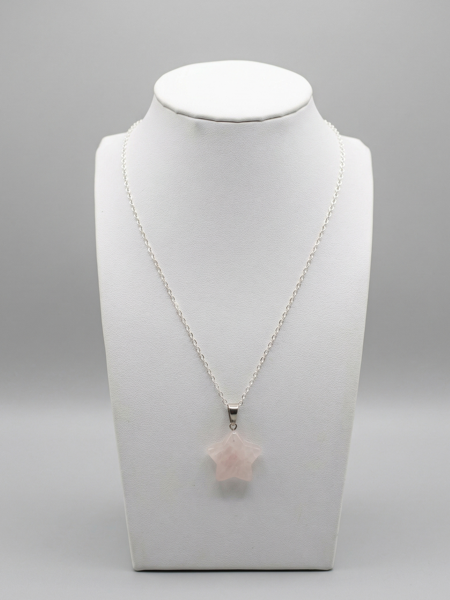 Necklace with a star-shaped pink pendant on a white mannequin bust against a gray background