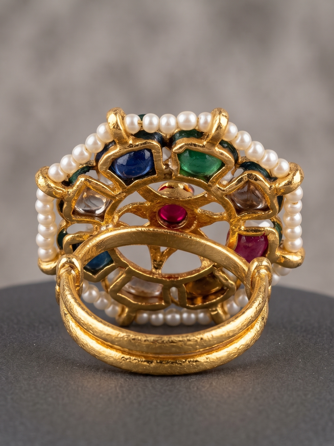Decorative ring with pearls and colored stones on a gray surface