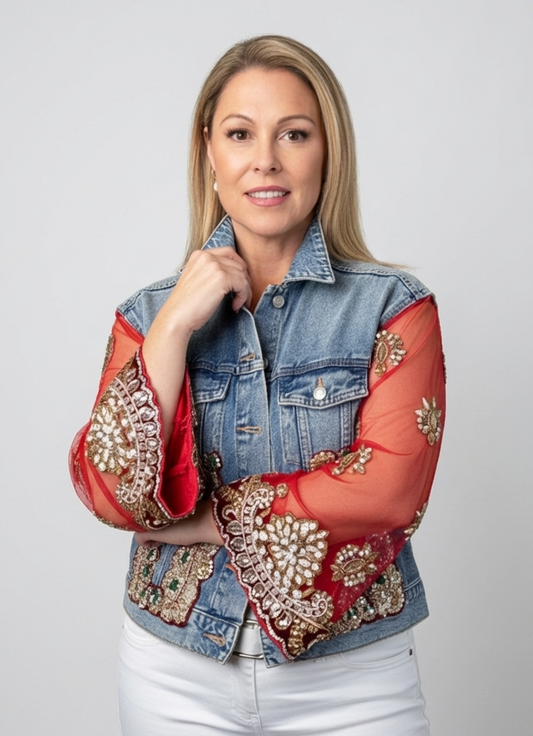Woman wearing a denim jacket with red sleeves and gold embellishments on a gray background