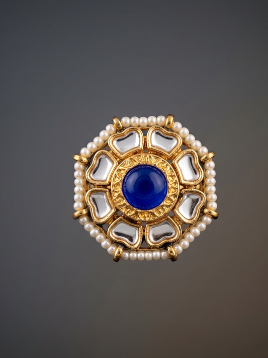Decorative brooch with blue center, pearls, and crystals on a dark background