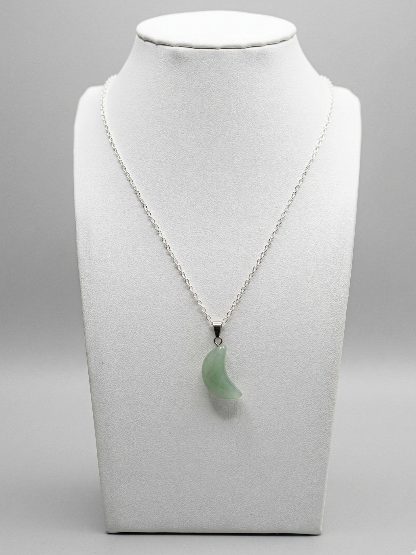 Necklace with a green pendant on a mannequin bust against a gray background