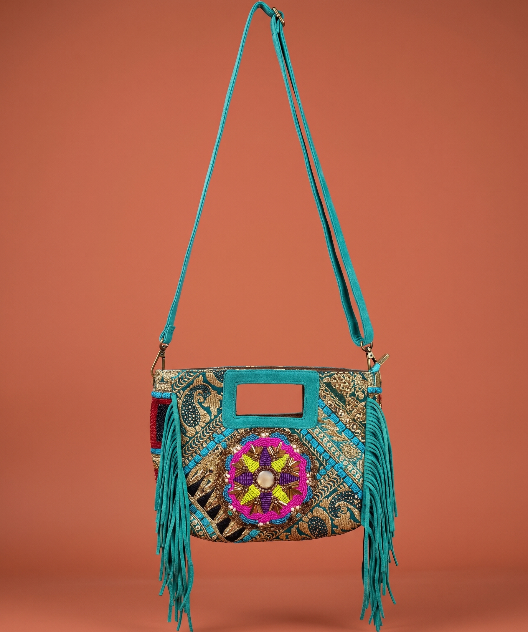 Turquoise handbag with colorful floral design and fringes on an orange background