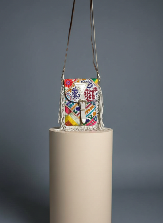 Colorful handbag with floral patterns on a cylindrical beige stand against a gray background