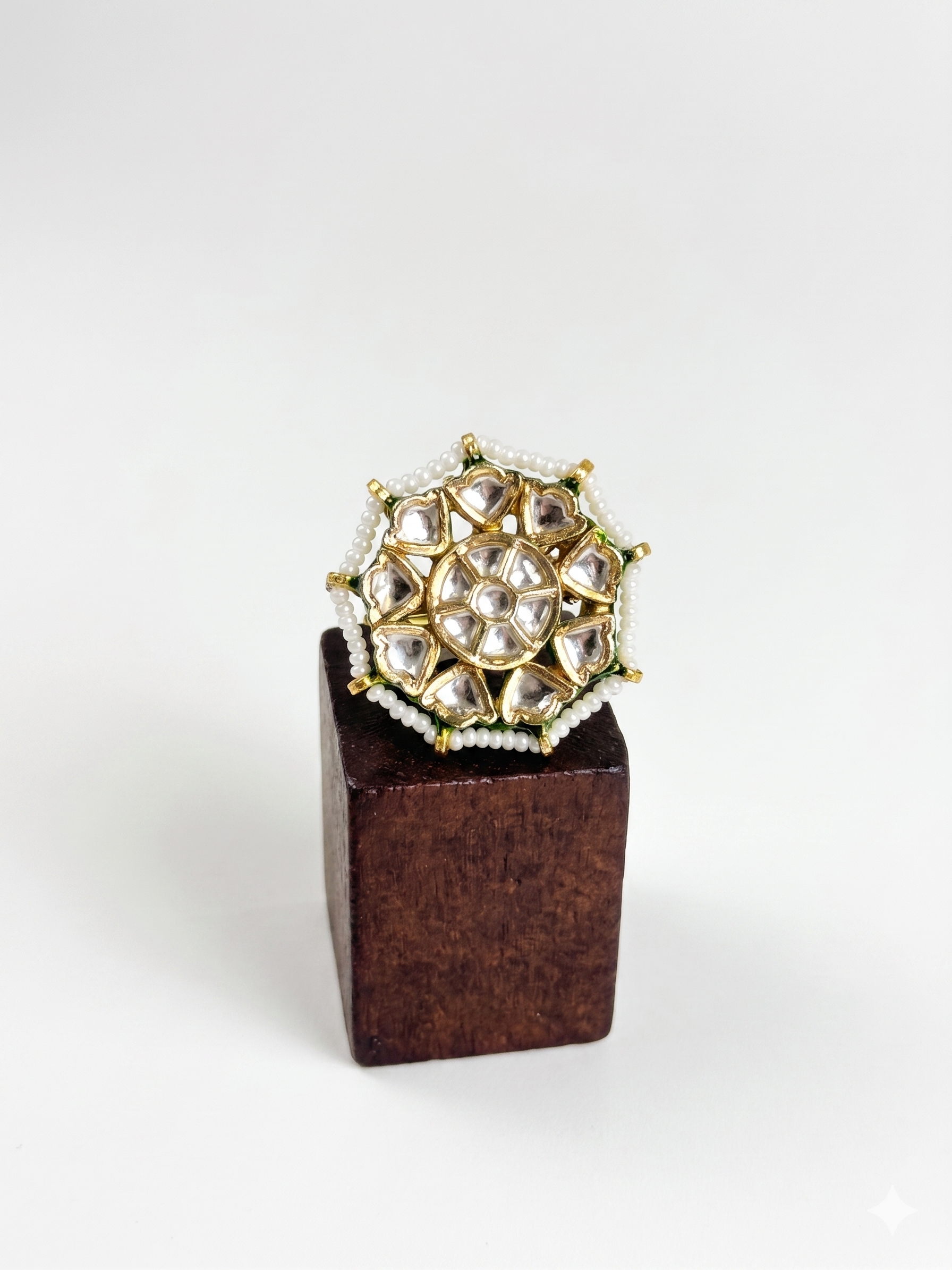 Gold and pearl ring on a wooden block against a white background