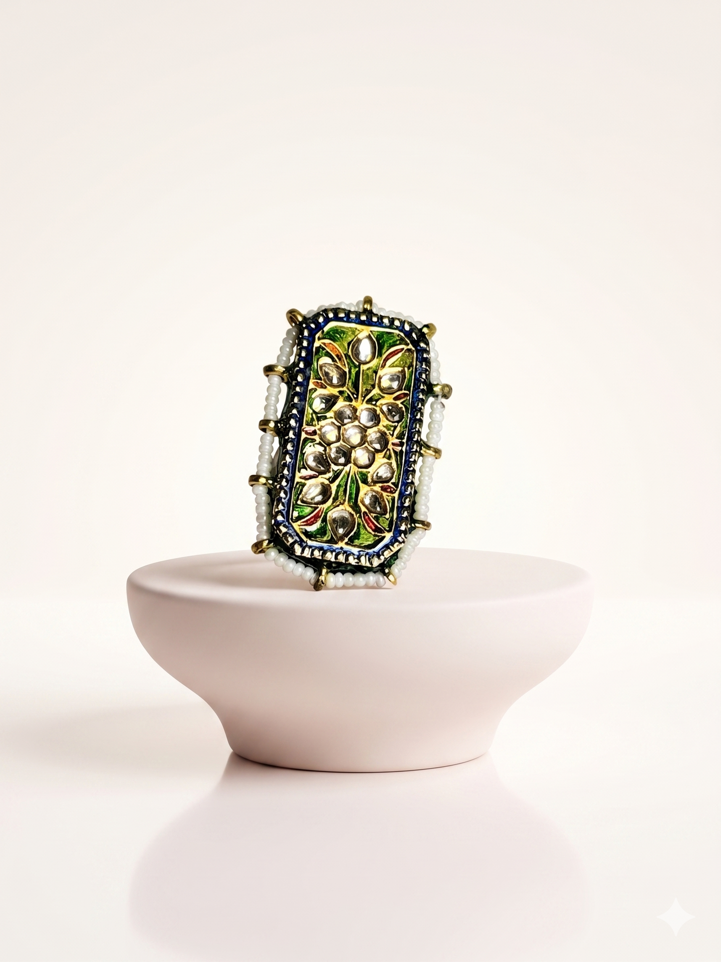 Decorative ring with intricate design on a white pedestal against a white background