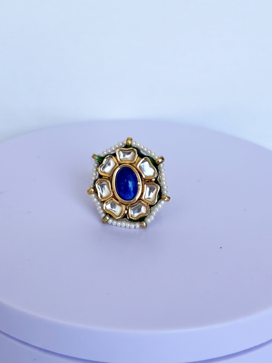 Bold handcrafted Kundan ring featuring a natural lapis lazuli center stone, crystal-inspired floral detailing, delicate pearl accents, and radiant 22Kt gold plating designed for timeless elegance.