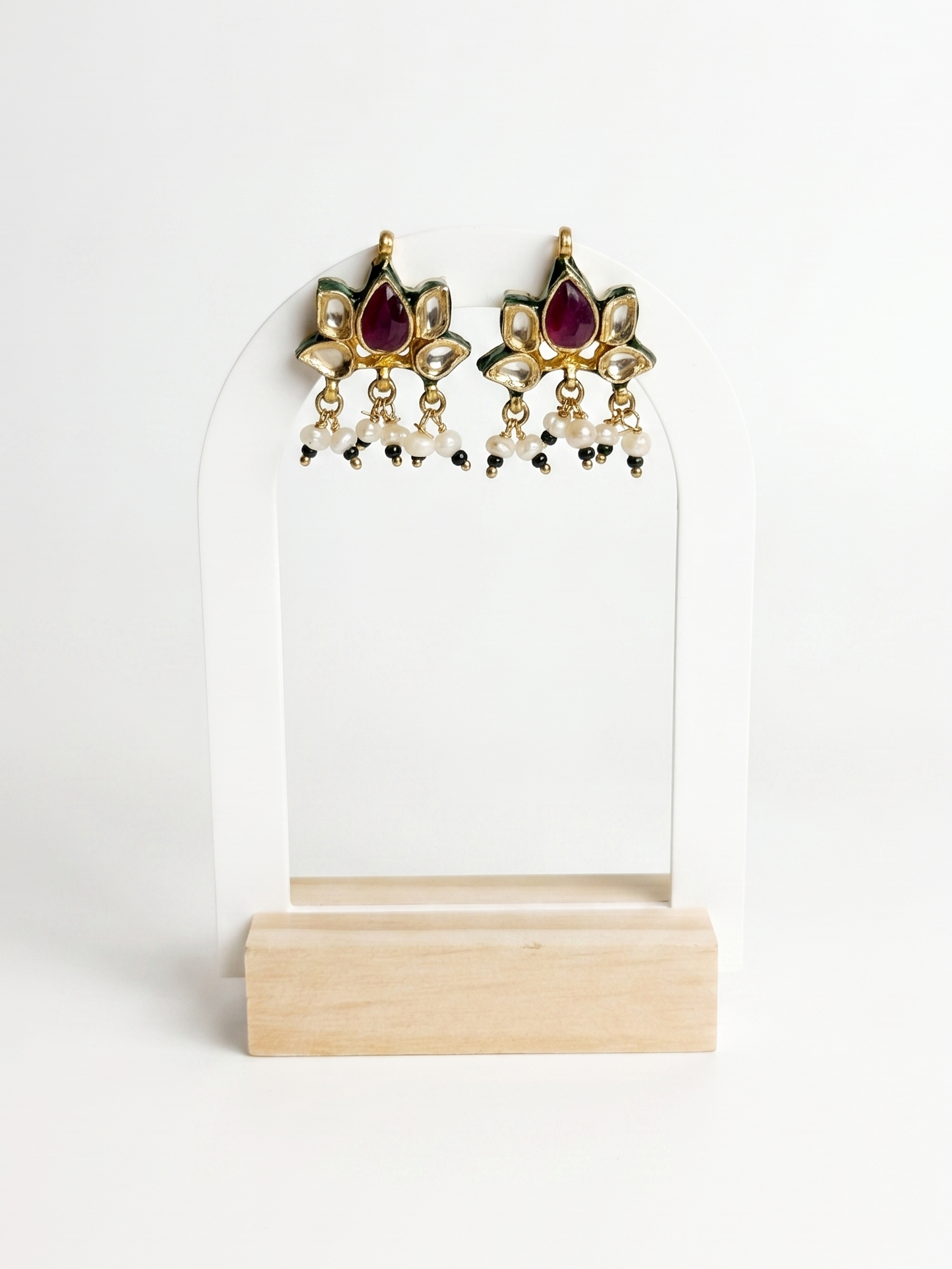 Pair of gold earrings with red gemstones on a white stand