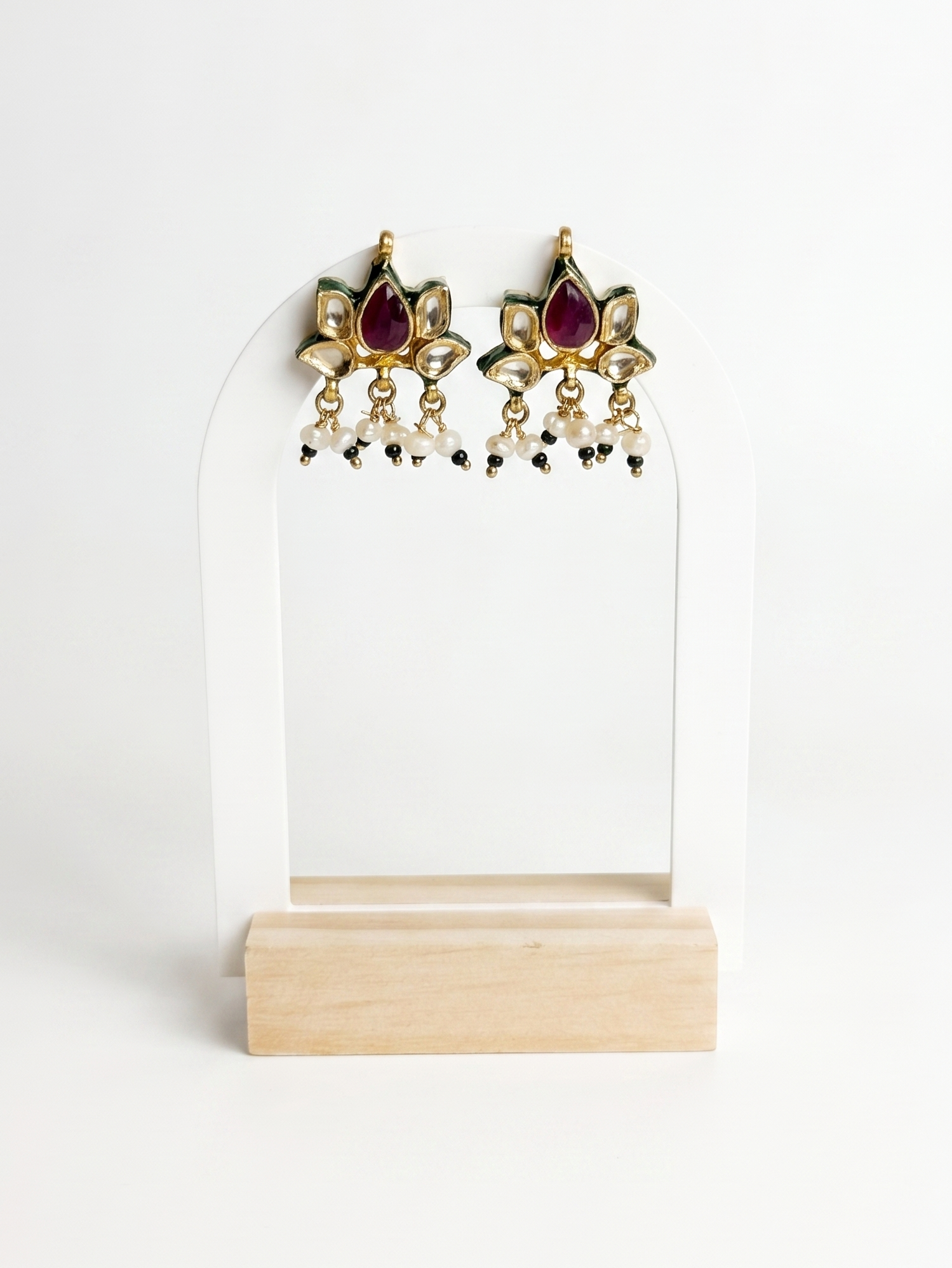 Pair of gold earrings with red gemstones on a white stand