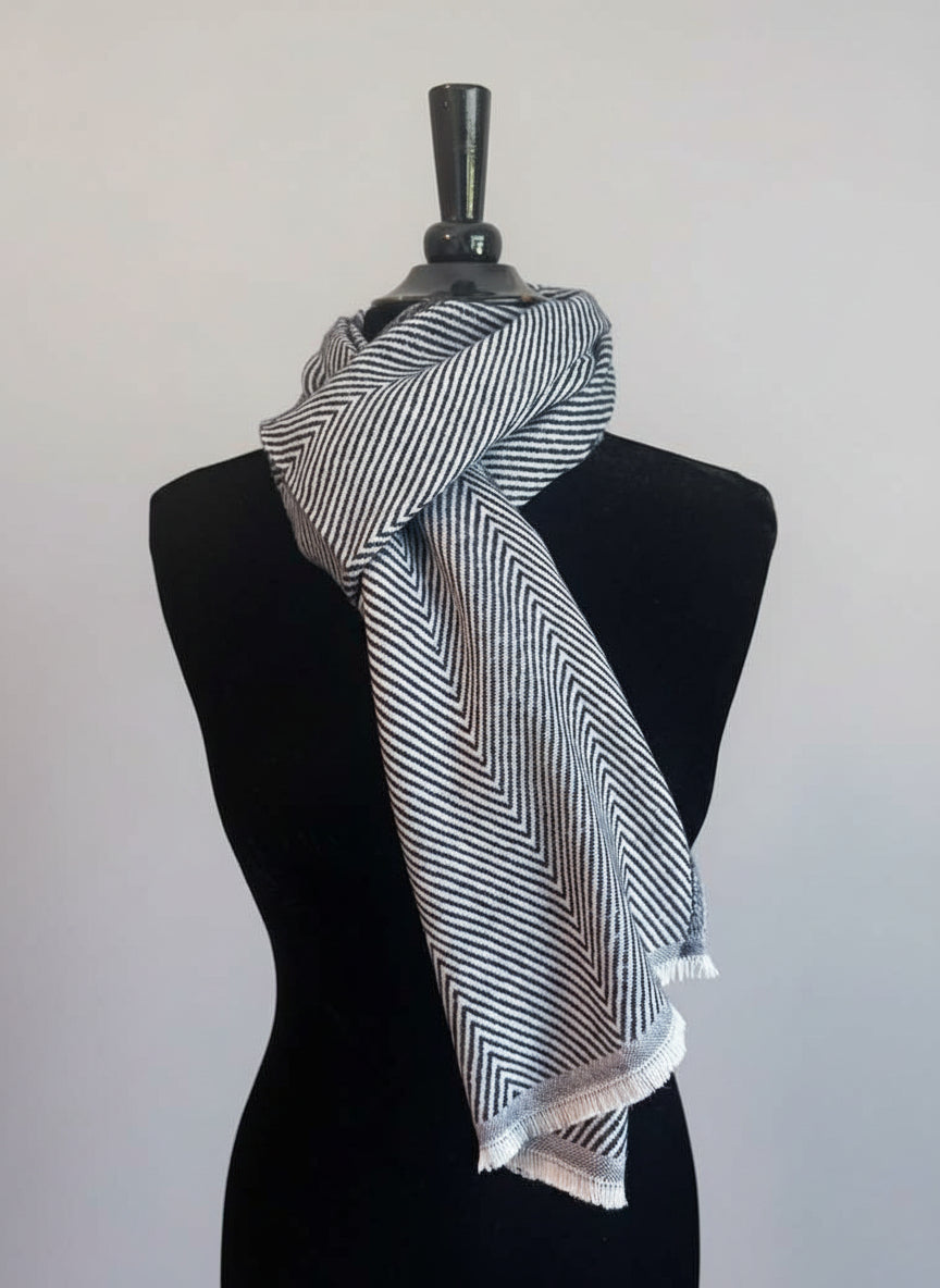 Mannequin wearing a black and white striped scarf against a plain background