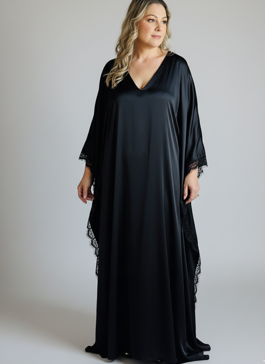 Woman wearing a black long dress with lace sleeves on a plain background