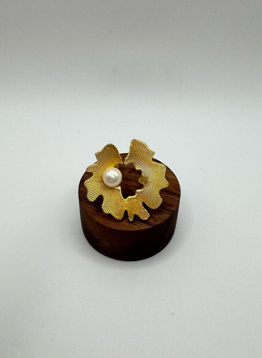 Small wooden object with a gold decorative element and pearl on a light gray background