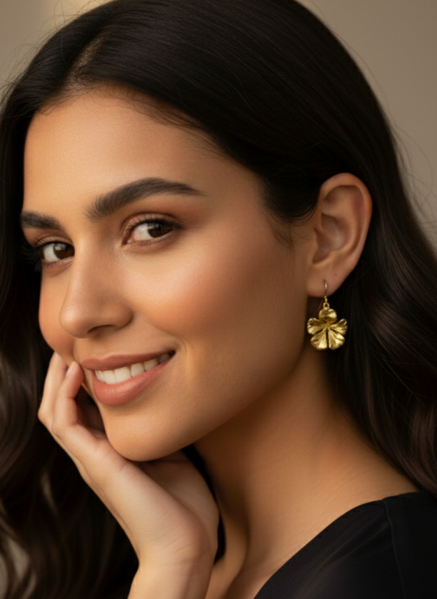 Woman with long dark hair wearing gold earrings against a neutral background