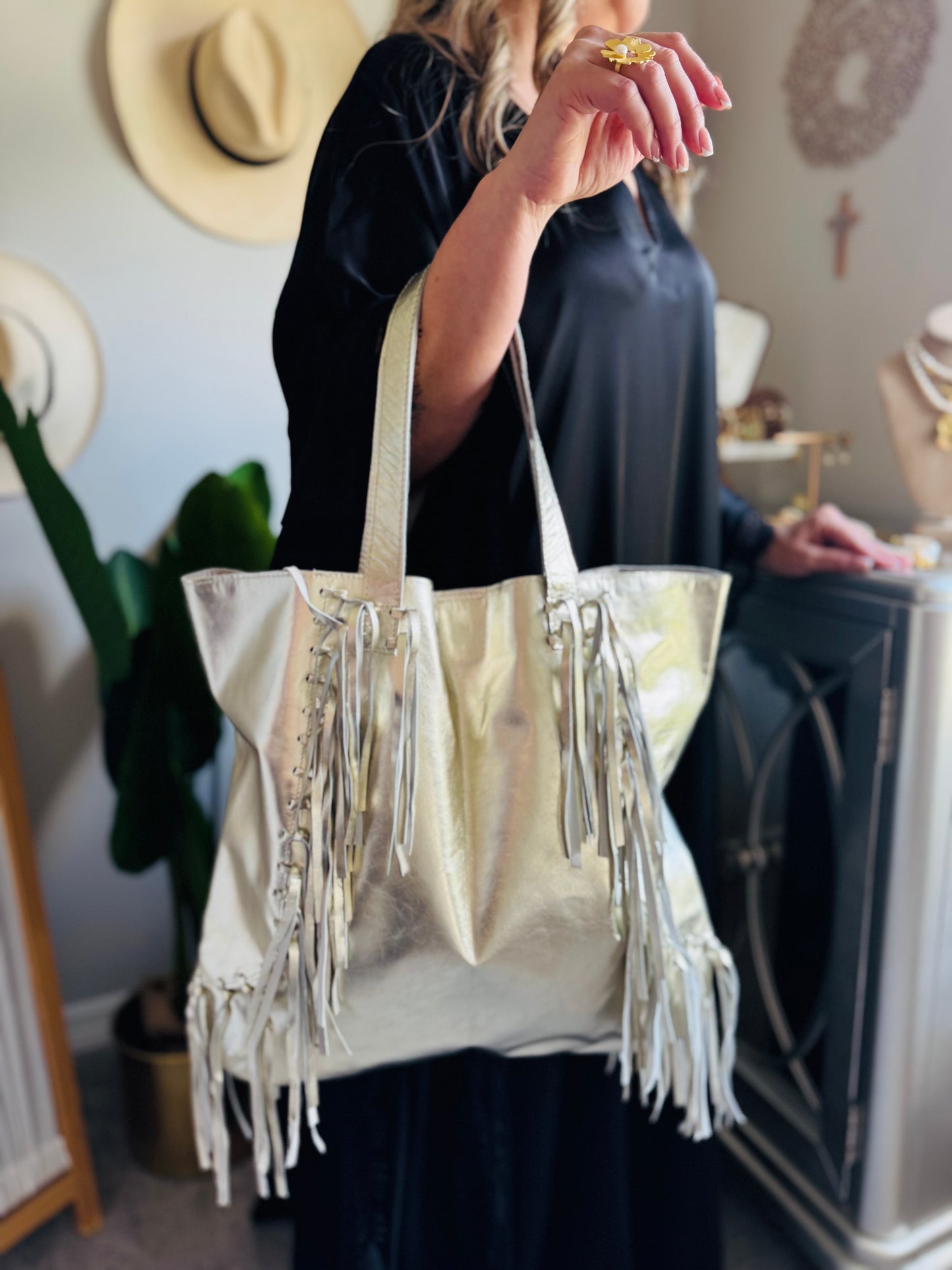 Person holding a silver fringe handbag in an indoor setting