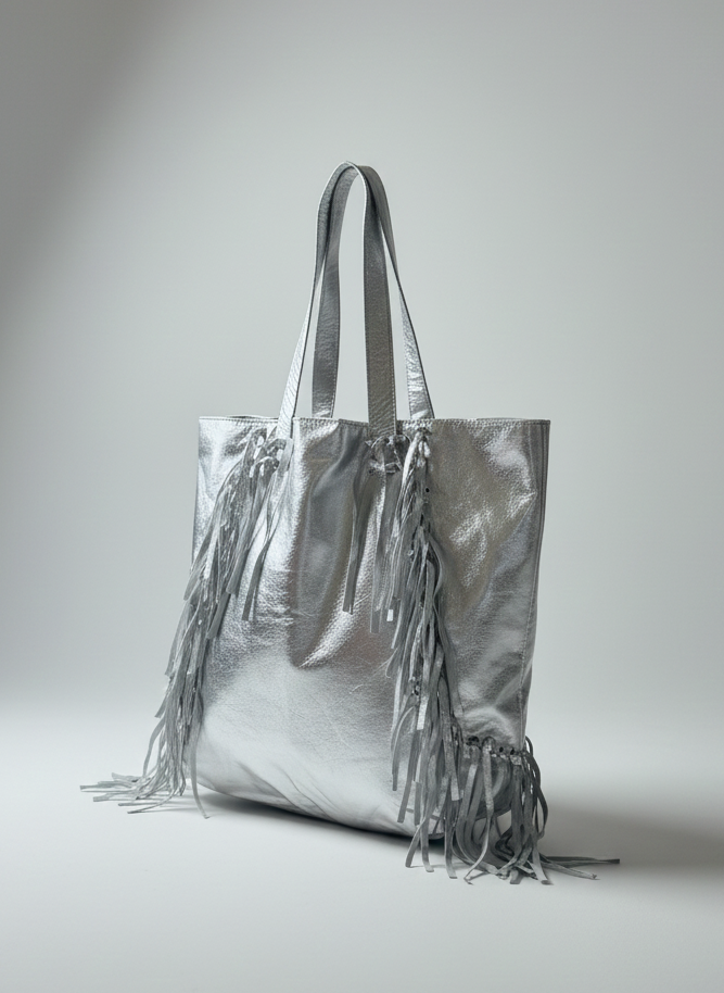 Silver tote bag with fringe details on a light gray background