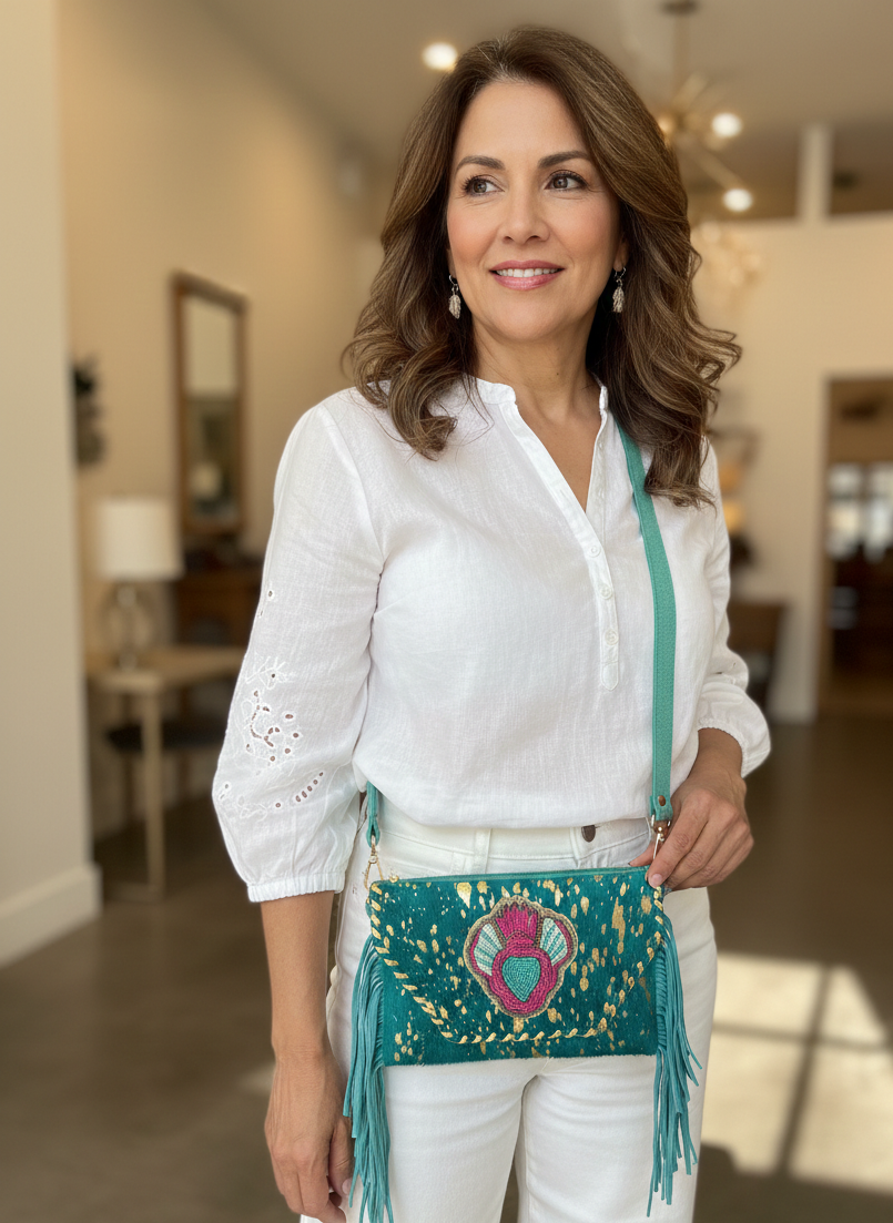 Woman holding a teal handbag with colorful patterns in an indoor setting