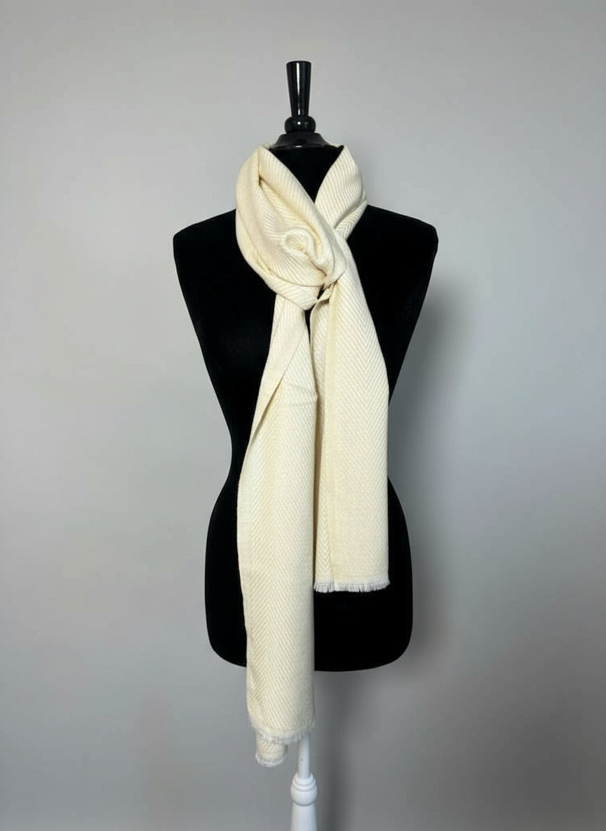 Mannequin wearing a cream scarf with a hat and jewelry display in the background.