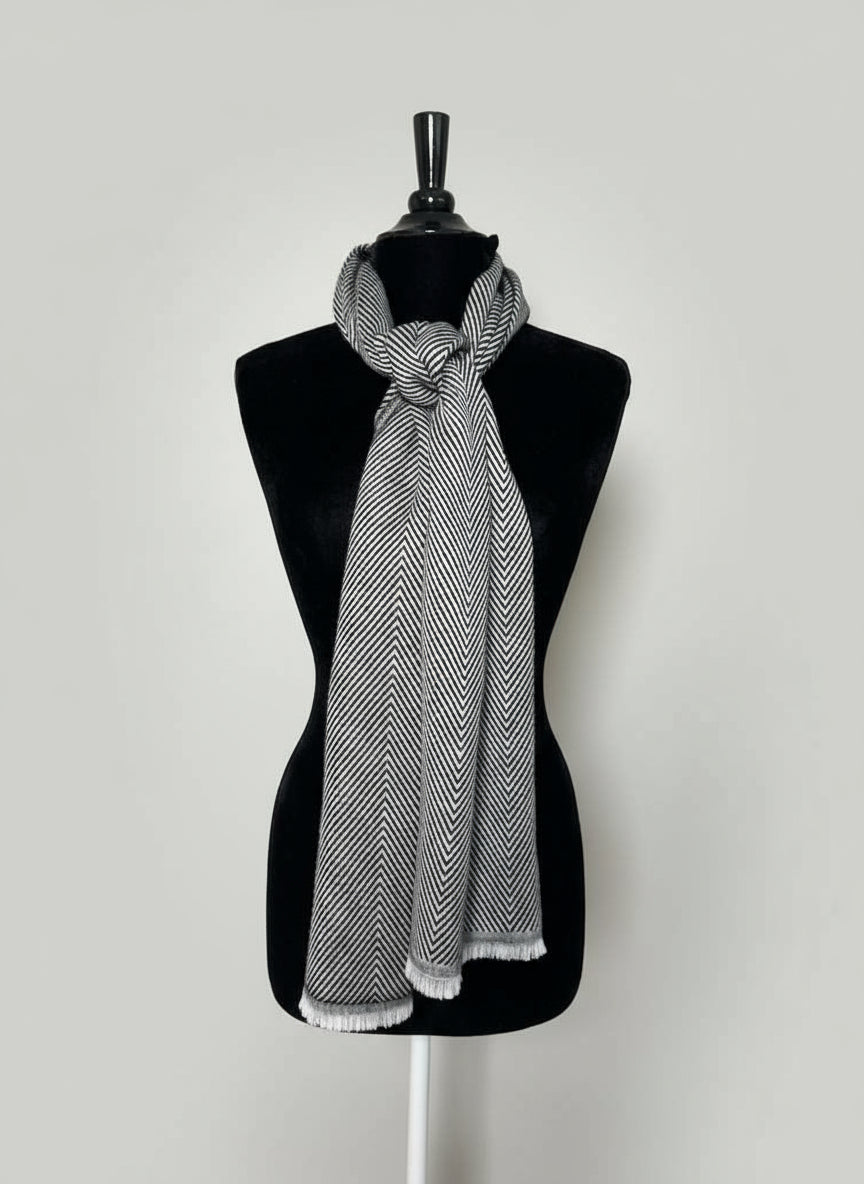 Mannequin wearing a black and white patterned scarf with a hat and jewelry display in the background.