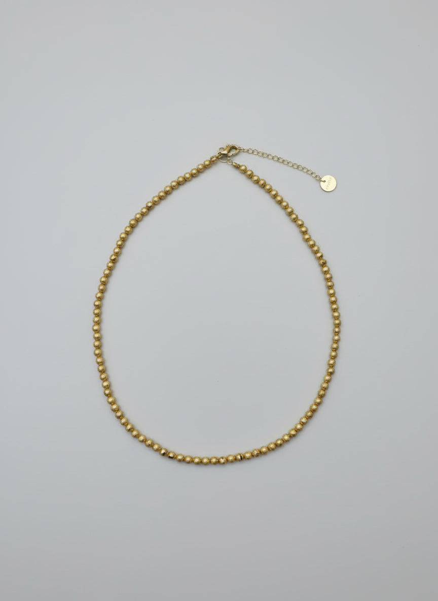 Gold necklace on a marble surface with a wooden and gold background