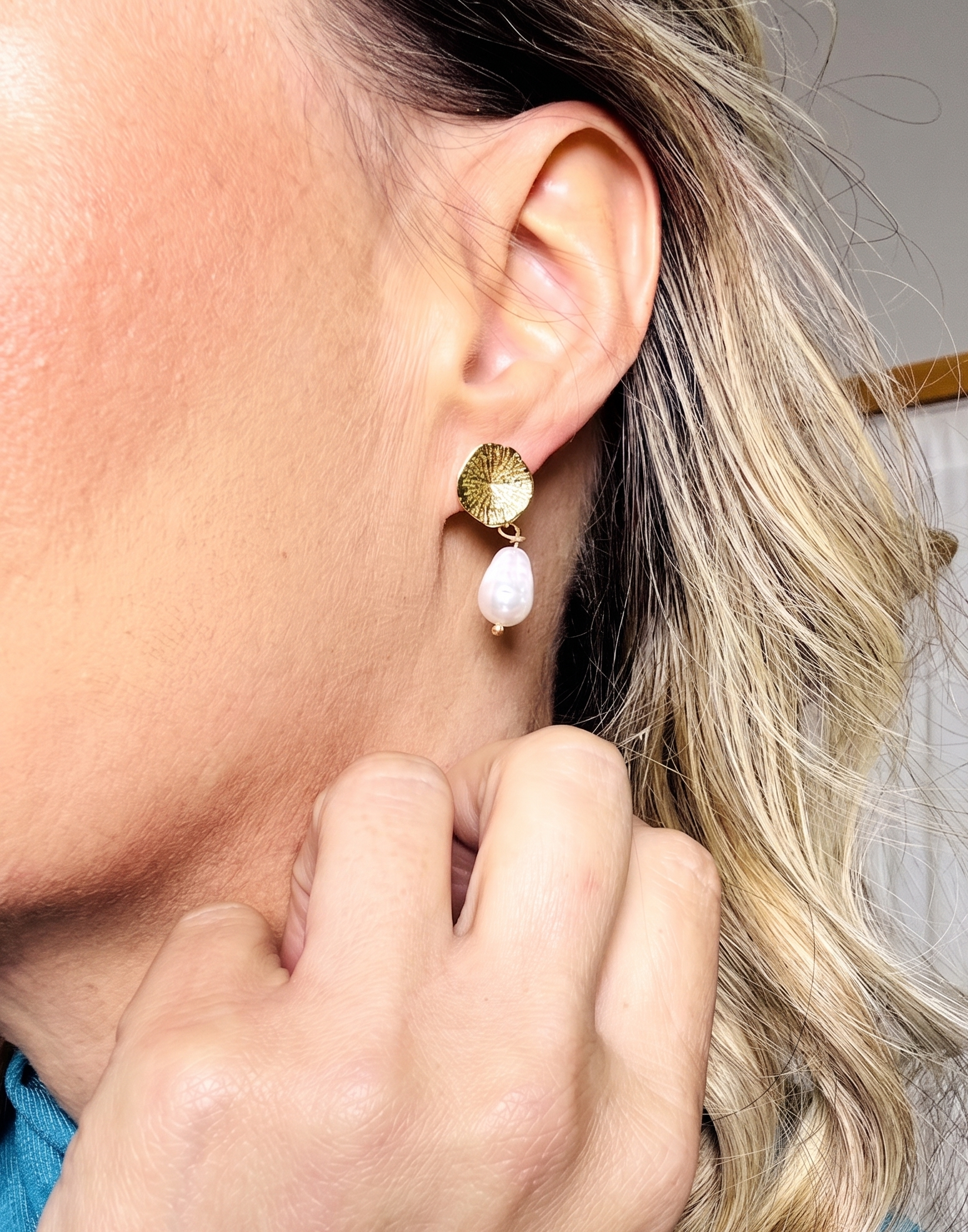 Close-up of a person wearing a gold and pink earring.