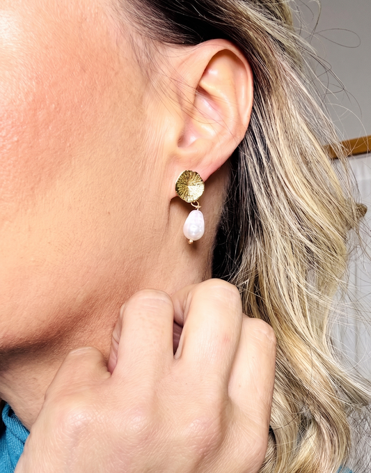 Close-up of a person wearing a gold and pink earring.