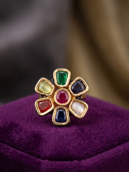 Flower-shaped ring with colorful gemstones on a purple cushion