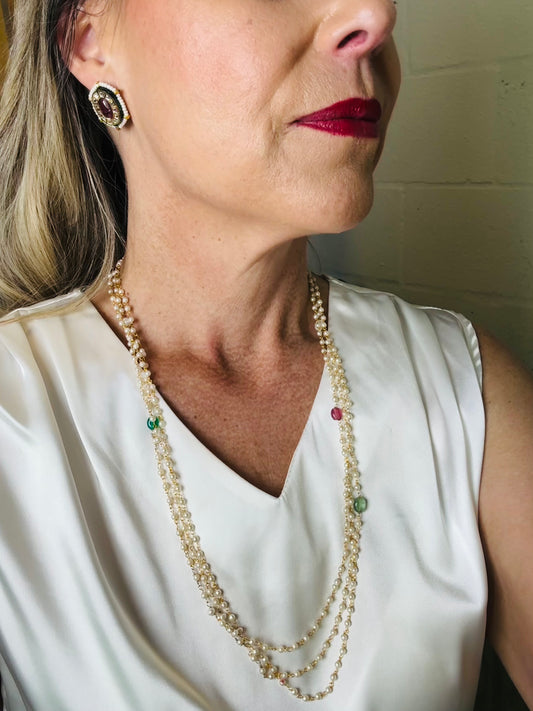 Woman wearing a pearl necklace with red lipstick and earrings.