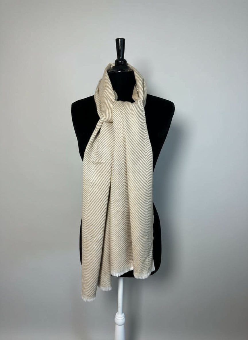 Mannequin wearing a beige scarf with a hat on a small table in the background.