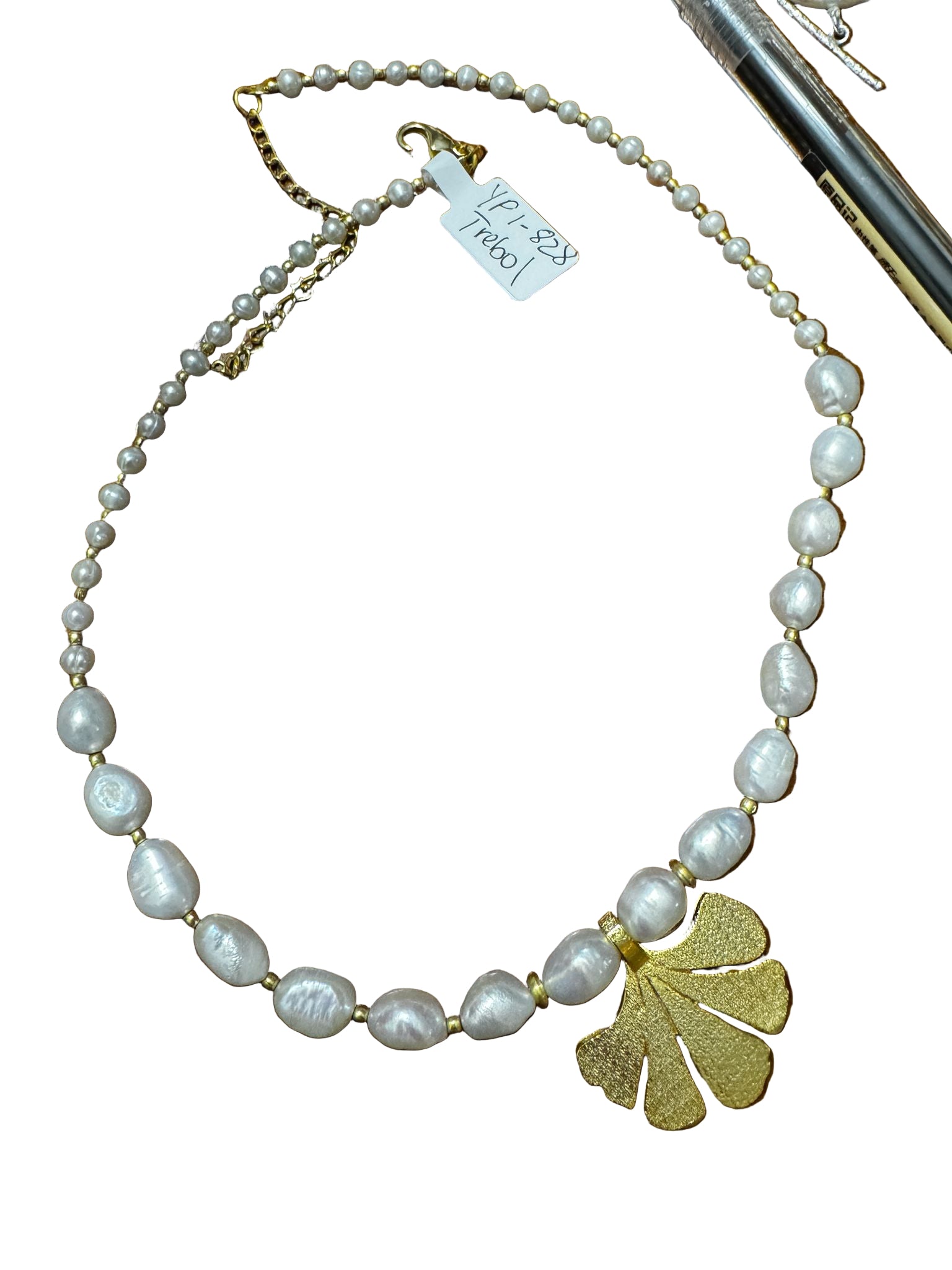 Pearl necklace with a gold leaf pendant on a wooden surface